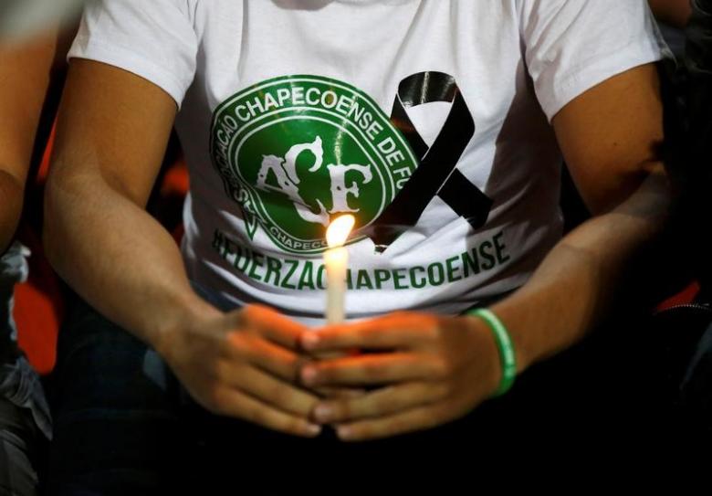 A fan of Atletico Nacional soccer club holds a candle and wears a shirt in support while paying tribute to the players of Brazilian club Chapecoense killed in the recent airplane crash, in Medellin, Colombia, November 30, 2016.  REUTERS/Jaime Saldarriaga