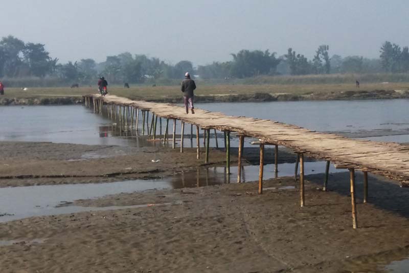 Locals cross a makeshift bamboo bridge over the Bakraha River in Govindapur-1 of Morang district, while putting their life at risk, on Tuesday, December 20, 2016. Photo: RSS