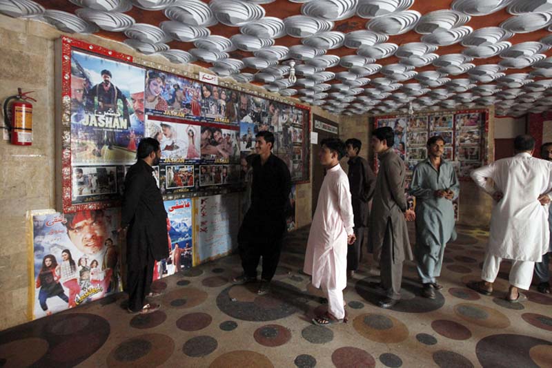 Pakistani cinema-goers look at photos displayed at a local cinema in Karachi, Pakistan, on Sunday, December 18, 2016. Photo: AP