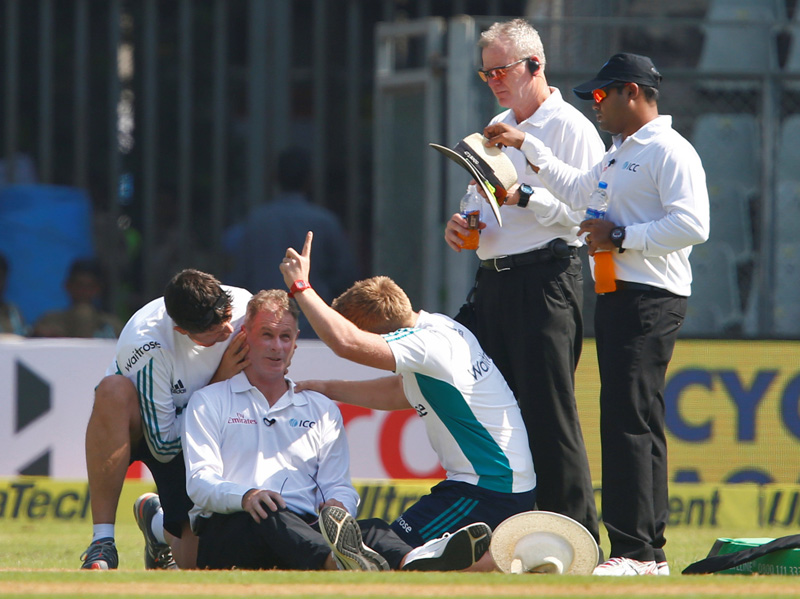 Umpire Paul Reiffel is helped by support staff. Photo: Reuters