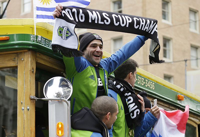 Seattle Sounders forward Nicolas Lodeiro (centre), holds up a MLS Cup Champions scarf as he rides a trolly with teammates during a celebration march, on Tuesday, December 13, 2016, in Seattle. The Sounders defeated Toronto FC on December 10, 2016 to win the MLS soccer championship. Photo: AP