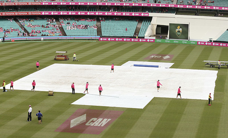 Grounds crew pull a tarpaulin over the wicket at the Sydney Cricket Ground as rain delays play during the cricket test match between Australia and Pakistan in Sydney, Australia, on Thursday, January 5, 2017. Photo: AP