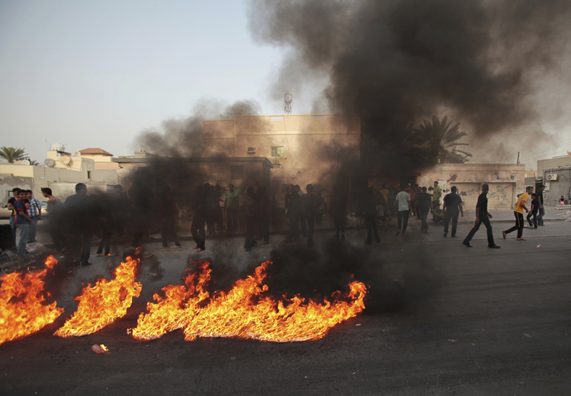 FILE- In this Friday, March 14, 2014 file photo, Bahraini anti-government protesters burn representations of the flag of Gulf countries' Peninsula Shield forces, during a protest in Malkiya, Bahrain. Photo: AP
