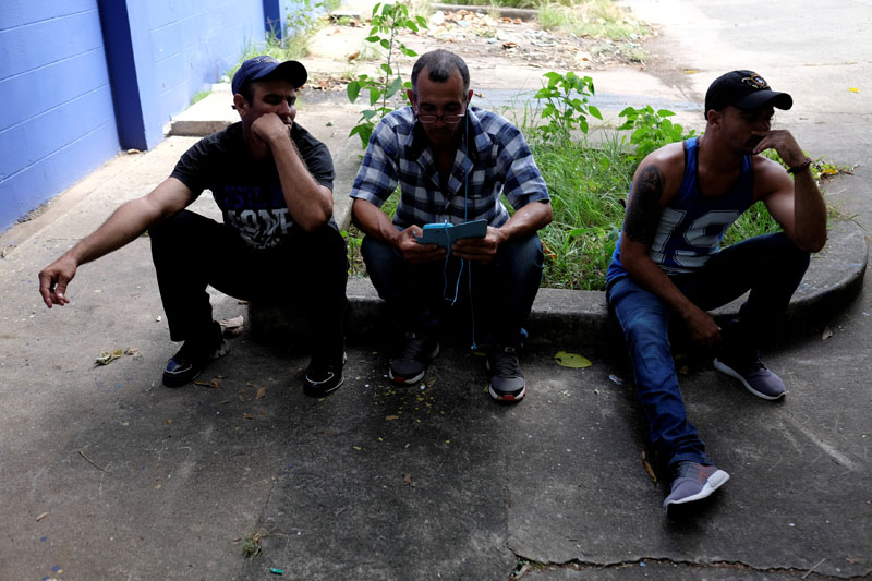 Cuban migrants listen and monitor international news on a cellphone outside the Caritas shelter in Panama City, Panama, on January 13, 2017. Photo: Reuters