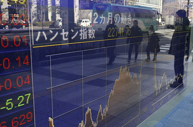 People are reflected on the electronic board of a securities firm in Tokyo, on Monday, January 16 2017. Photo: AP