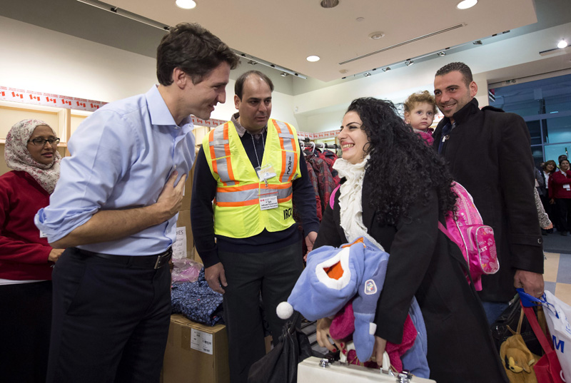 FILE - In this Dec. 11, 2015 file photo, Prime Minister Justin Trudeau, left, greets Georgina Zires, center, Madeleine Jamkossian, second right, and her father Kevork Jamkossian, refugees fleeing from Syria, as they arrive at Pearson International airport, in Toronto. Photo: AP