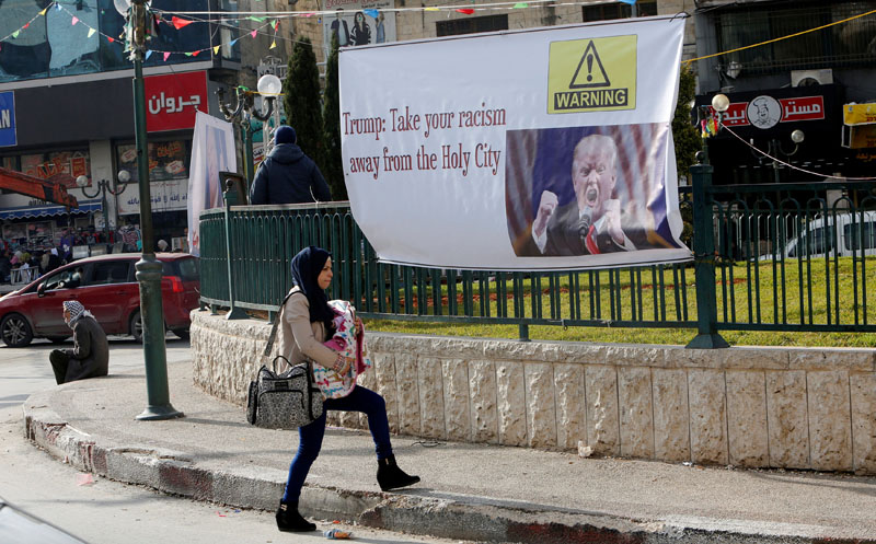 A Palestinian woman walks past a banner against a promise by US President-elect Donald Trump to relocate the US embassy to Jerusalem, in the West Bank city of Nablus on January 19, 2017. Photo: Reuters