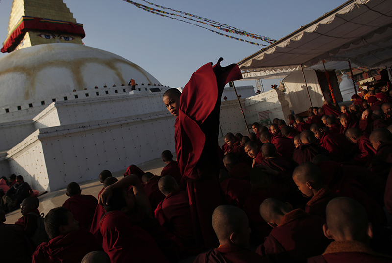 A Buddhist monk adjusts his robes as he participates in Nyigma Monlam prayers at the Bouddhanath Stupa in Kathmandu, on Tuesday.