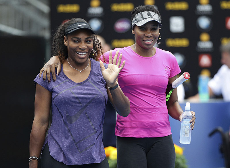 United States' Serena Williams (left) waves to the crowd as she walks onto the court with her sister Venus during an exhibition event ahead of the ASB Classic tennis tournament in Auckland, New Zealand, on Sunday, January 1, 2017. Photo: Doug Sherring/New Zealand Herald via AP