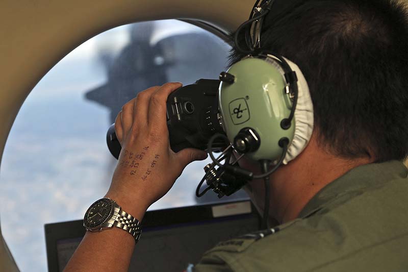 File-Flight Officer Jack Chen uses binoculars at an observers window on a Royal Australian Air Force P-3 Orion during the search for missing Malaysia Airlines Flight MH370 in Southern Indian Ocean, Australia on March 22, 2014. Photo: AP