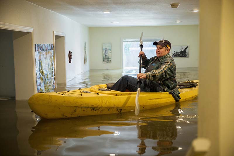 Lorin Doeleman uses a kayak to check her flooded home in Guerneville, California on Wednesday, January 11, 2017. Photo: San Francisco Chronicle via AP