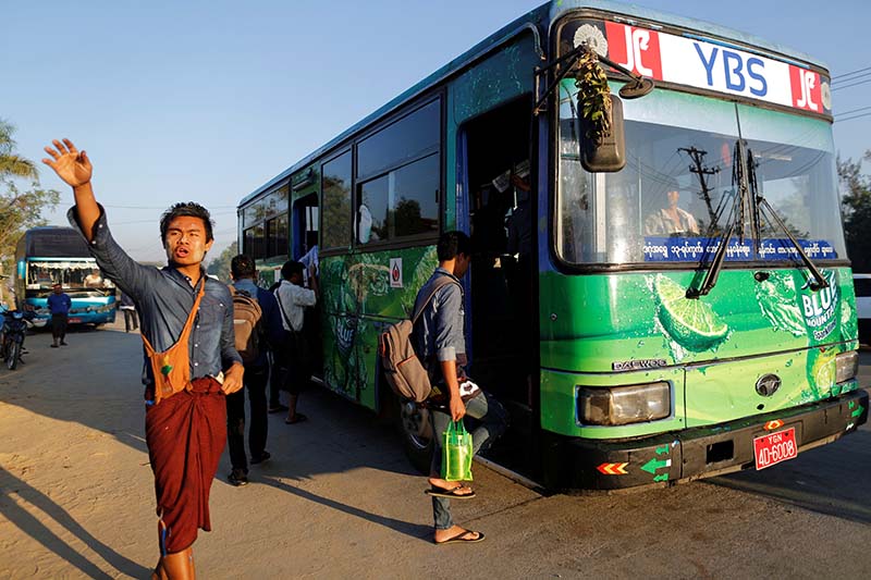 An assistant driver waves to passengers in Yangon, Myanmar, on Monday January 16, 2017. Photo: Reuters