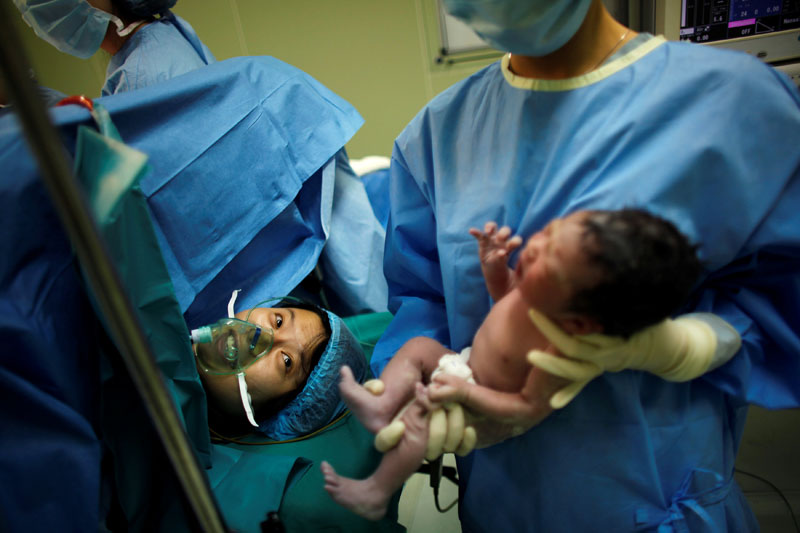 File - Yang Huiqing looks at her baby after a cesarean section in Ruijin Hospital in Shanghai on October 24, 2011. Photo: Reuters