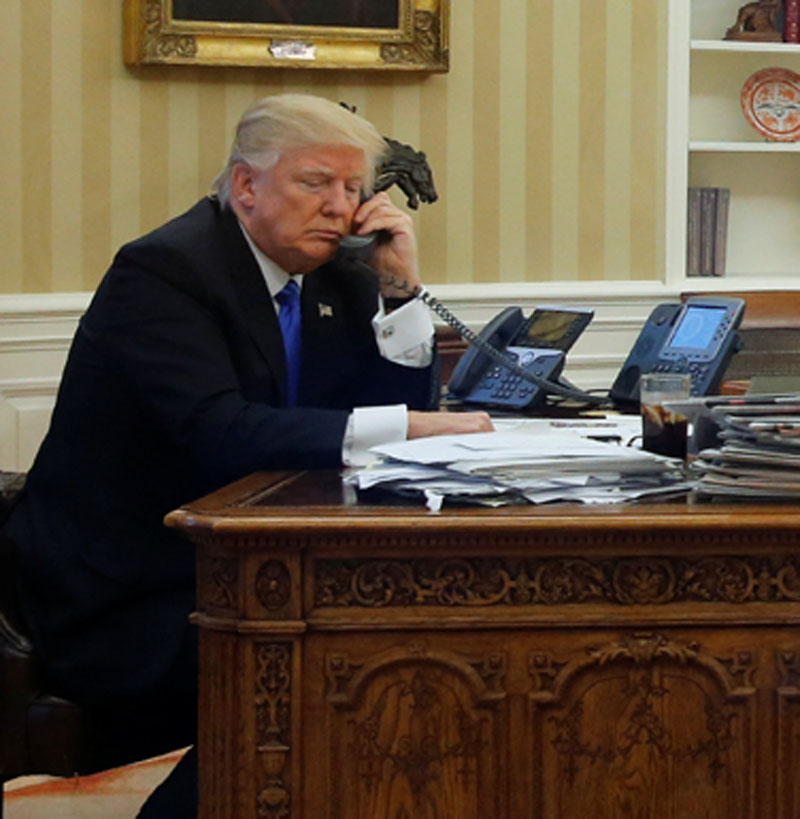 US President Donald Trump (left), seated at his desk with National Security Advisor Michael Flynn (second from right) and senior advisor Steve Bannon (right), speaks by phone with Australia's Prime Minister Malcolm Turnbull in the Oval Office at the White House in Washington, US, on January 28, 2017. Photo: Reuters