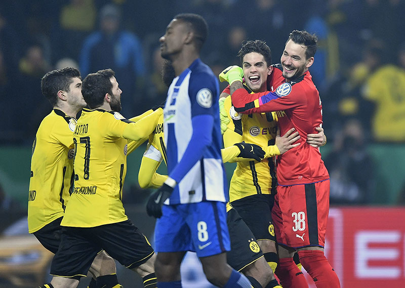 Dortmund's players celebrate Dortmund goalkeeper Roman Buerki, right, behind Hertha's Salomon Kalou, center in front, after winning the German Soccer Cup match between Borussia Dortmund and Hertha BSC Berlin after penalty shootout in Dortmund, Germany, on Wednesday, Feb. 8, 2017. Kalou missed the last penalty. Photo: AP