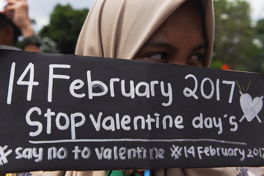 A Muslim student holds a poster during a protest against Valentine's Day celebrations in Surabaya, Indonesia, February 13, 2017 in this photo taken by Antara Foto. Picture taken February 13, 2017. Antara Foto/Zabur Karuru/ via REUTERS 