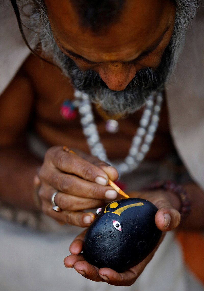 A Hindu holy man, or sadhu, paints Lord Shiva on the shaligram stone as he sits on the premises of Pashupatinath Temple during the Shivaratri festival in Kathmandu, on Friday, February 24, 2017. Photo: Reuters