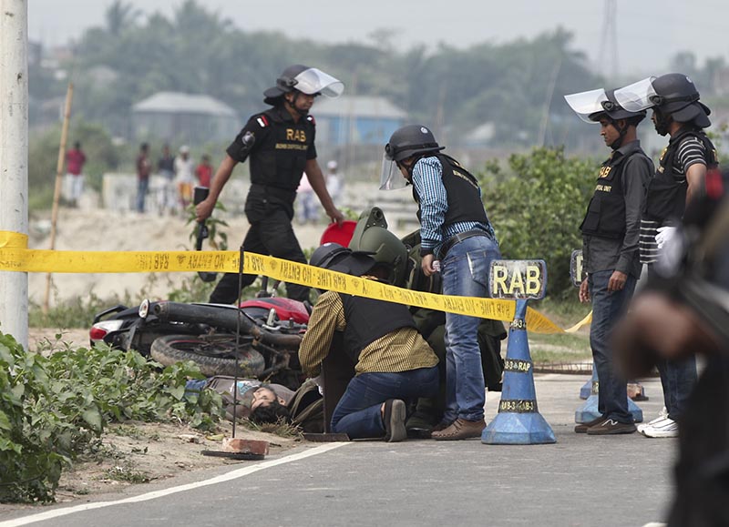 Bangladesh Rapid Action Battalion (RAB) personnel and bomb experts inspect the body of a man beside a RAB checkpoint in Khilgaon, Dhaka, Bangladesh, on Saturday, March 18, 2017. Photo: AP