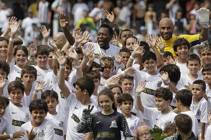 FILE - Former soccer star Pele (centre top) and his son Edson Cholbi do Nascimento (above at right) wave with children during during the centennial anniversary celebration of the team in Santos, Brazil, on April 14, 2012. Photo: AP