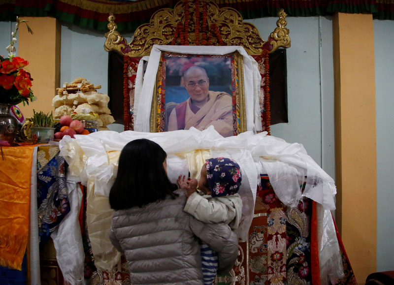 A Tibetan woman carrying a child offers prayer on the portrait of exiled Tibetan spiritual leader, the Dalai Lama, during a function to mark the Tibetan Uprising Day at the Tibetan Refugee camp in Lalitpur, Nepal March 10, 2017. Photo: Reuters