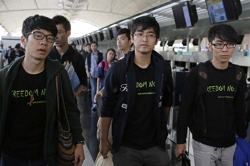 FILE - Hong Kong Federation of Students leader Alex Chow, center, committee members Eason Chung, right, and Nathan Law react after they denied permission to travel to Beijing, at Hong Kong International Airport in Hong Kong, on November 15, 2014. Photo; AP