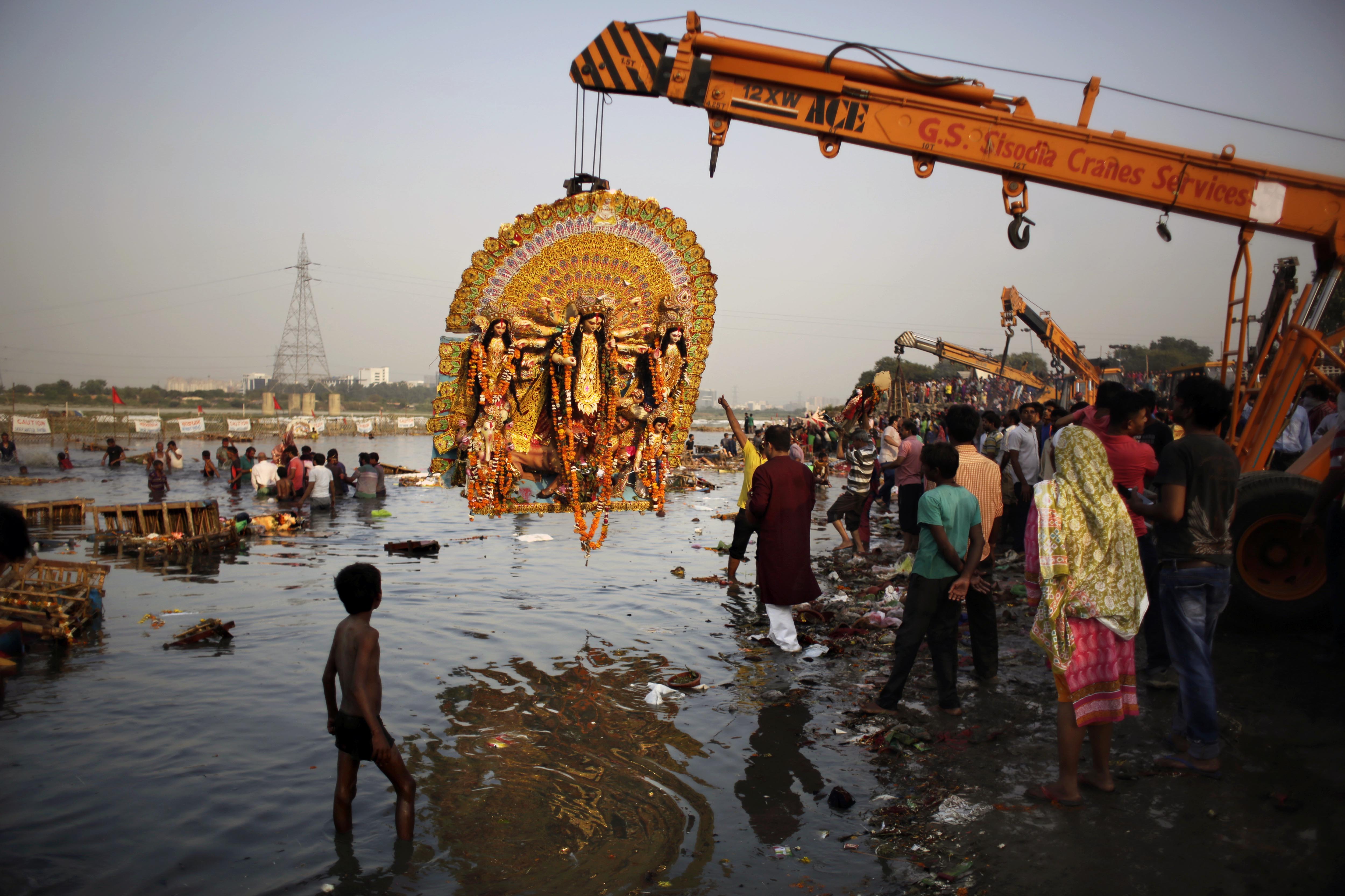 FILE- In this Tuesday, Oct. 11, 2016 file photo, a giant Idol of Hindu goddess Durga suspends from a crane before it is immersed in the River Yamuna during Durga Puja festival in New Delhi, India. A court in northern India has granted the same legal rights as a human to the Ganges and Yamuna rivers, considered sacred by nearly a billion Indians. The Uttaranchal High Court in Uttarakhand state ruled Monday, March 20, 2017,  that the two rivers be accorded the status of living human entities, meaning that if anyone harms or pollutes the rivers, the law would view it as no different from harming a person. (AP Photo/Altaf Qadri, File)