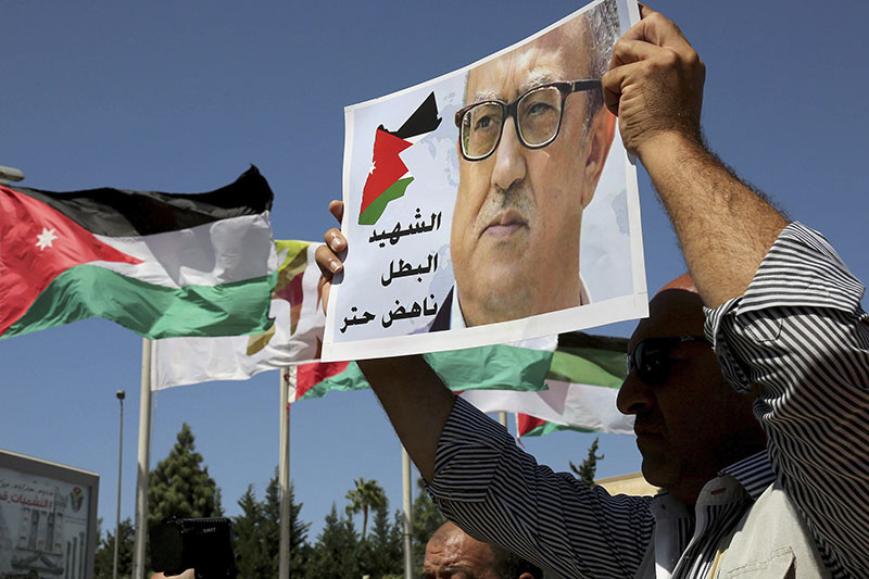 FILE - Relatives of Jordanian writer Nahed Hattar hold up signs protesting his death, in front of Jordanian Prime Ministry in Amman, Jordan, on Monday, September 26, 2016. Photo: AP