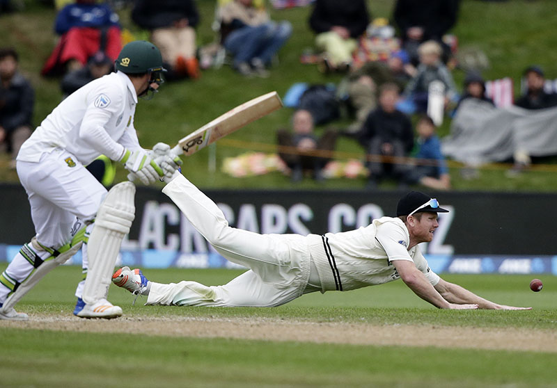 New Zealand's Jimmy Neesham (right) dives to stop take the ball as South Africa's Dean Elgar watches during day four of the first cricket test at University Oval, Dunedin, New Zealand, on Saturday, March 11, 2017. Photo: AP