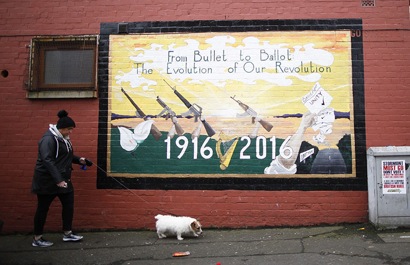 A woman walks her dog past a Republican mural in West Belfast, Northern Ireland, on Thursday, March 2, 2017. Photo: AP