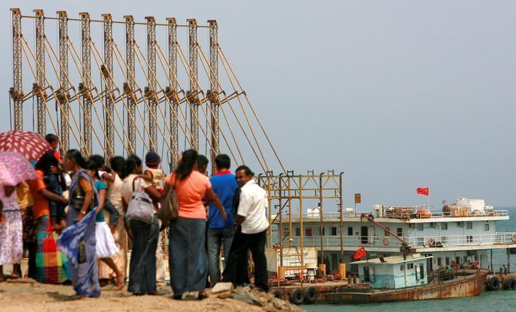 A group of Sri Lankan visitors at the new deep water shipping port watch Chinese dredging ships work in Hambantota, 240 km (150 miles) southeast of Colombo, March 24, 2010.  REUTERS/Andrew Caballero-Reynolds/Files