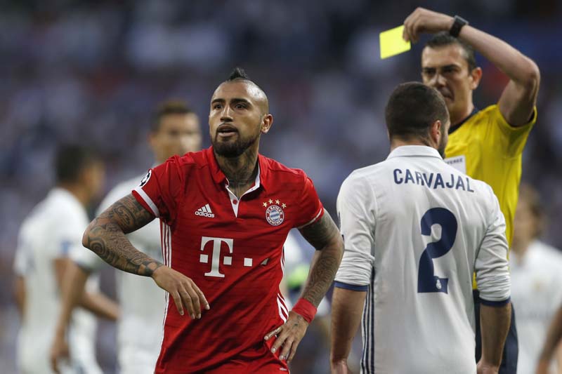 Referee Viktor Kassai of Hungary shows a yellow card to Bayern's Arturo Vidal (left), during the Champions League quarterfinal second leg soccer match between Real Madrid and Bayern Munich at Santiago Bernabeu stadium in Madrid, Spain, on Tuesday April 18, 2017. Photo: AP