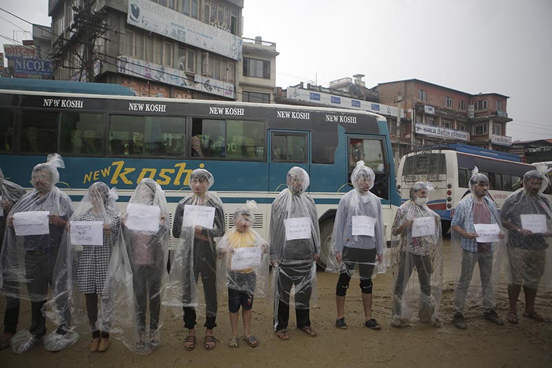 Activists stand wrapped in plastic sheet with ropes tied around their necks to protest against air pollution.