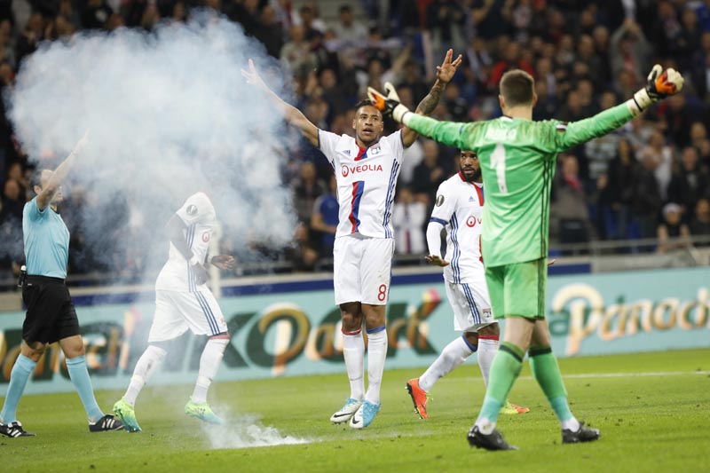 Smoke from something thrown onto the pitch as Lyon's Corentin Tolisso (center), celebrates scoring a goal during the Europa League quarterfinal soccer match between Lyon and Besiktas, in Decines, near Lyon, central France, on Thursday, April 13, 2017. Photo: AP