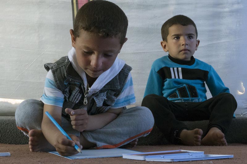 6-year-old, Mustafa (left), draws on a piece of paper next to another child in a tent, at the Khazer refugee camp in east Mosul, Iraq, on Wednesday, April 5, 2017. Photo: AP