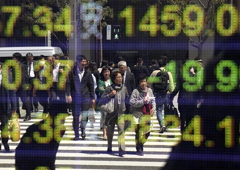 People are reflected on an electronic stock indicator of a securities firm in Tokyo, on Thursday, April 13, 2017. Photo: AP