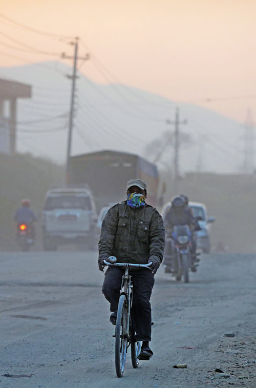 IA man covers his face as he rides on a dusty road in Kathmandu on March 1, 2017. Photo: AFPnNepal's government is trying to tackle rising pollution levels in the smog-choked Kathmandu Valley, but standing in the way is a powerful bus mafia that controls the capital's roads. The rulers of Kathmandu's roads are a web of transport syndicates made up of private bus owners that have repeatedly blocked official attempts to modernise the highly inefficient bus network.n / AFP PHOTO / PRAKASH MATHEMA / TO GO WITH AFP STORY Nepal-pollution-transport,FOCUS by Ashok Dahal and Annabel Symington