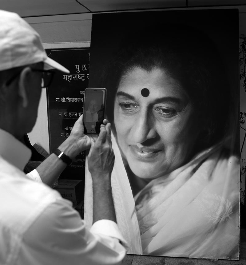 A man takes a photograph of a giant portrait of Indian musician Kishori Amonkar in Mumbai, India, on Tuesday, April 4, 2017. Photo: AP