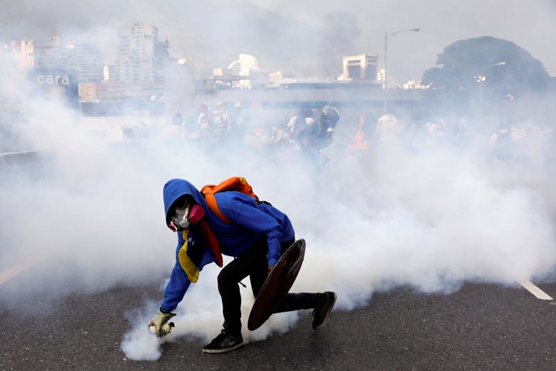 A demonstrator throws back a tear gas grenade at the riot police while rallying against Venezuela's President Nicolas Maduro in Caracas, Venezuela, on April 24, 2017. Photo: Reuters