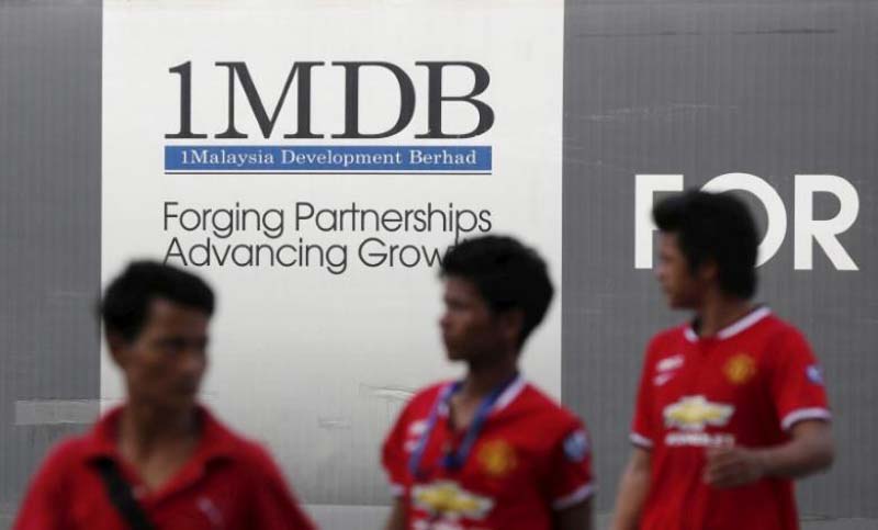 Men walk past a 1 Malaysia Development Berhad (1MDB) billboard at the fund's flagship Tun Razak Exchange development in Kuala Lumpur, on March 1, 2015. Photo: Reuters