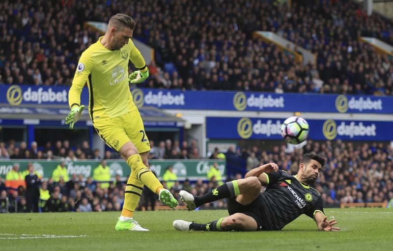 Chelsea's Diego Costa slides in on Everton goalkeeper Maarten Stekelenburg, for which he is later booked, during their English Premier League soccer match at Goodison Park, Liverpool, England, on Sunday, April 30, 2017. Photo: Nigel French/PA via AP