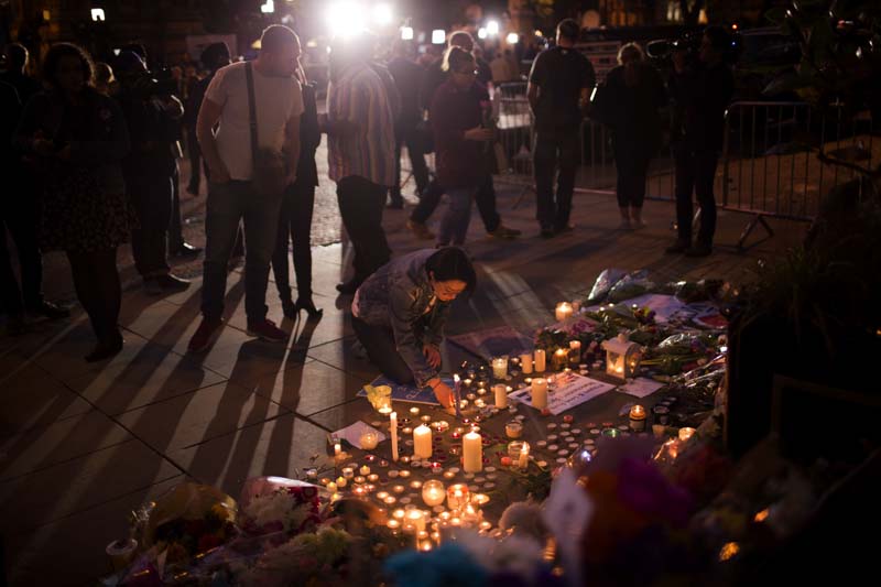 A woman lights candles after a vigil in Albert Square, Manchester, England, onTuesday, May 23, 2017, the day after the suicide attack at an Ariana Grande concert that left 22 people dead as it ended on Monday night. Photo: AP