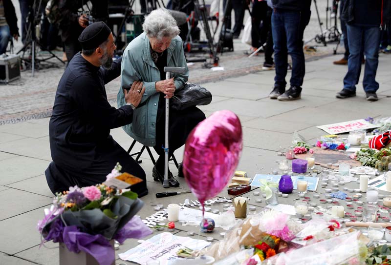 A Muslim man named Sadiq Patel comforts a Jewish woman named Renee Rachel Black next to floral tributes in Albert Square in Manchester, Britain, on May 24, 2017. Photo: Reuters