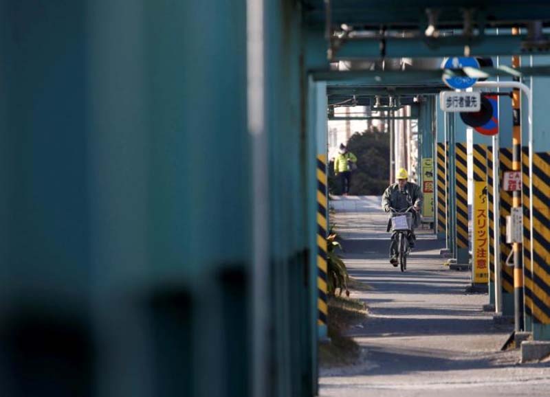 A worker cycles near a factory at the Keihin industrial zone in Kawasaki, Japan February 28, 2017. Photo: Reuters