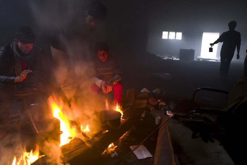 FILE - Unaccompanied minor, Ali, 12, a migrant from Jalalabad, Afghanistan, sits while cooking on a fire in an abandoned warehouse where he and other migrants took refuge in Belgrade, Serbia, on Saturday, February 4, 2017. Photo: AP