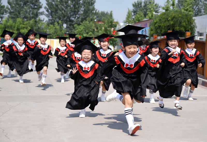 Children in gowns and mortarboards run with smiles during their kindergarten graduation ceremony in a kindergarten in Handan, Hebei province, China, on June 20, 2017. Photo: China Daily via Reuters