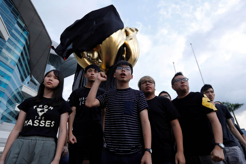 Pro-democracy activist Joshua Wong (centre) chants slogans after covering the Golden Bauhinia, a gift from China at the 1997 handover, with black cloth to demand full democracy ahead of 20th anniversary of the handover from British to China, in Hong Kong, on June 26, 2017. Photo: Reuters