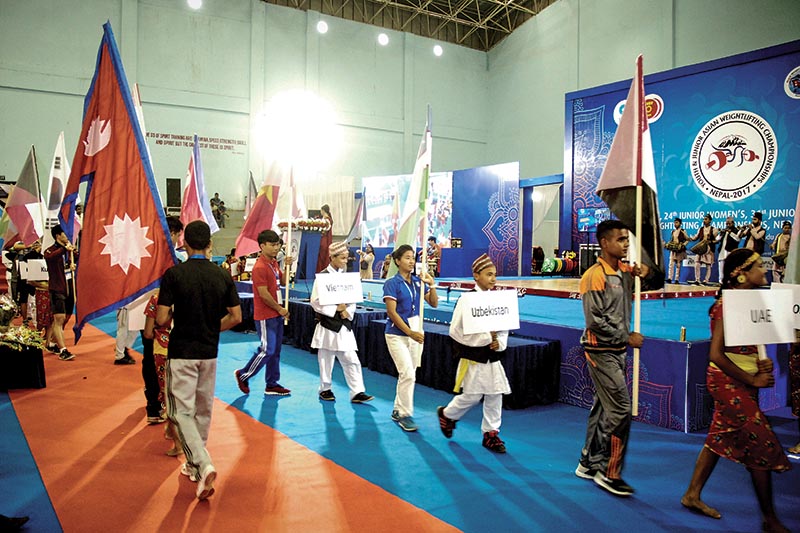 Volunteers carry national flags of participating countries during the opening ceremony of the Youth and Junior Asian Weightlifting Championships in Lalitpur, on Sunday. Photo: THT