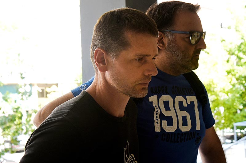 Alexander Vinnik, a 38 year old Russian man (left) suspected of running a money laundering operation, is escorted by a plain-clothes police officer to a court in Thessaloniki, Greece, on July 26, 2017. Photo: Reuters
