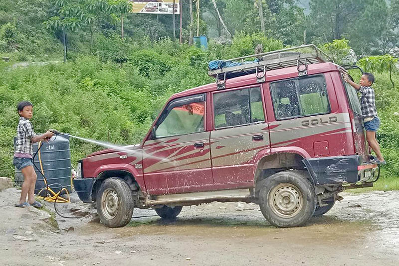 Two minor children, employed by a local hotel in Deurali along Pharping-Hetaunda raod section in Makwanpur District, are seen washing a vehicle, on Sunday, July 16, 2017. Photo: Ram Sarraf