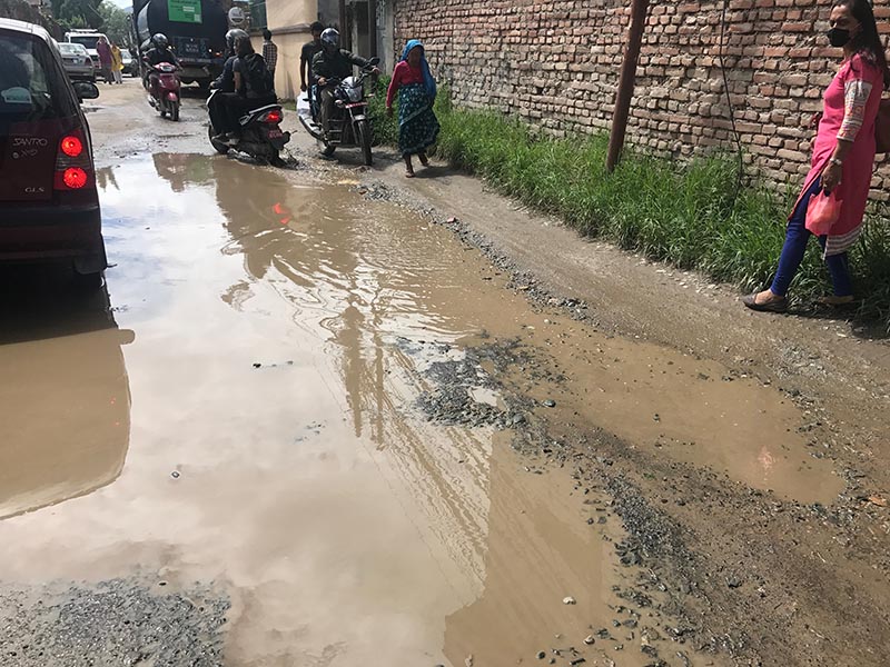 Vehicles passing through a pool of water on a badly damaged road, in Lalitpur, on Wednesday, July 26, 2017. Photo: THT